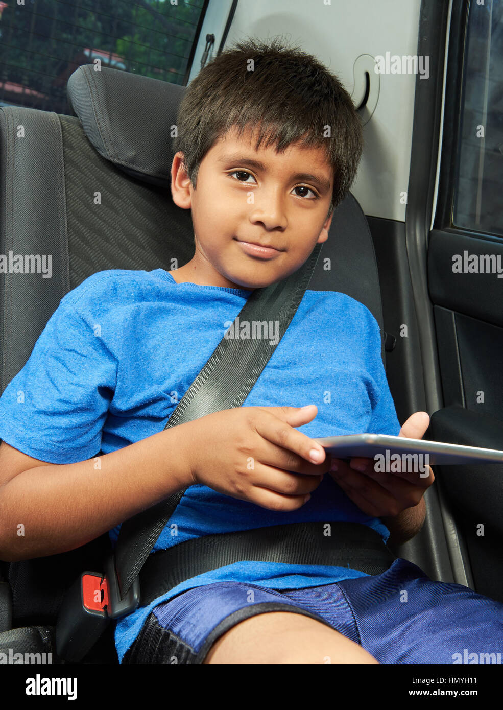 Latino Boy mit Tablet im Rücksitz des Wagens Stockfoto