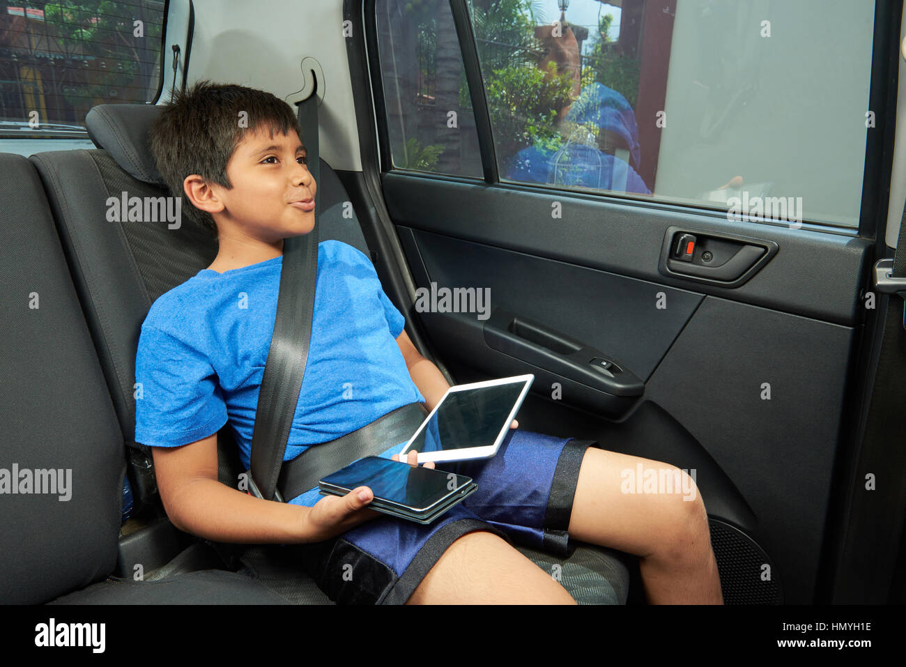 süsser Boy mit Tablet und Smartphone im Auto Stockfoto