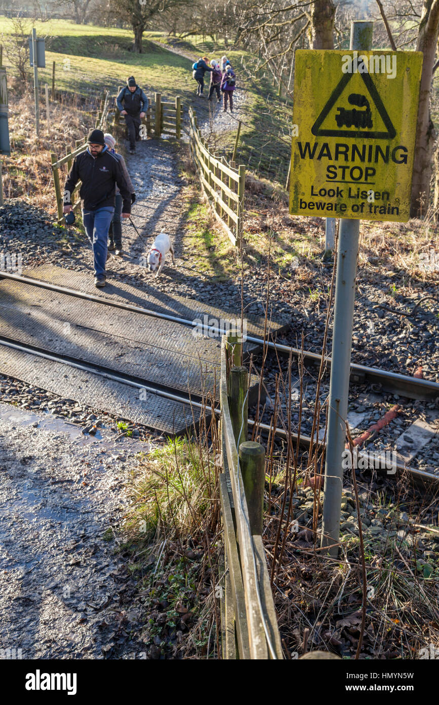"Warnung. Stoppen, schauen, hören, Hüten Sie sich vor dem Zug "Zeichen. Wanderer mit einem Fußgängerüberweg auf einer einzigen Spur Eisenbahnlinie, Hoffnung, Derbyshire, England, UK Stockfoto