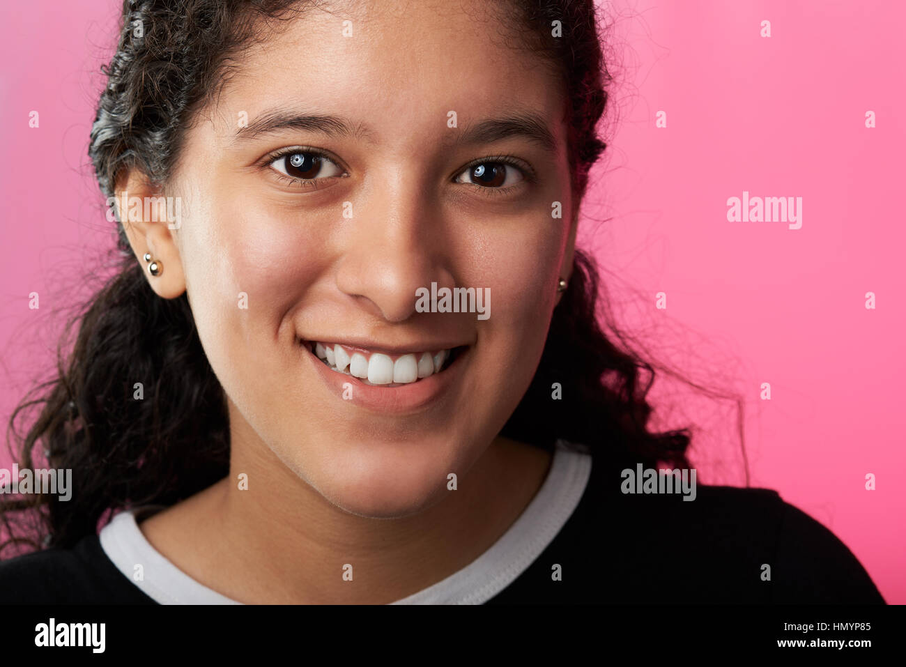 Latino Mädchen mit lockigem Haar auf rotem Hintergrund isoliert Stockfoto