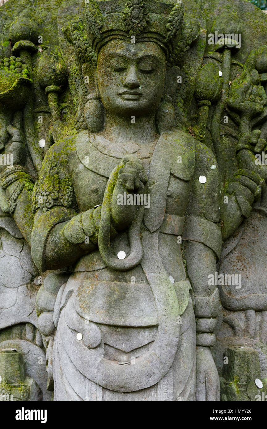 Ein Moos bedeckt Avalokiteshvara-Statue in einem botanischen Garten. Stockfoto