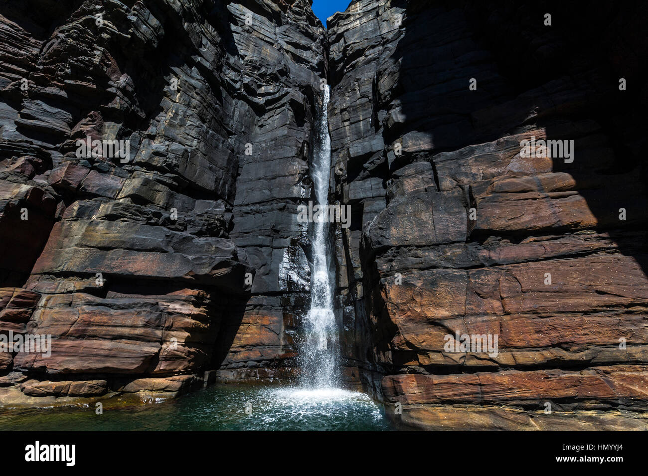 Ein Wasserfall Kaskaden hinunter eine schiere Sandstein in Cyanobakterien bedeckt. Stockfoto