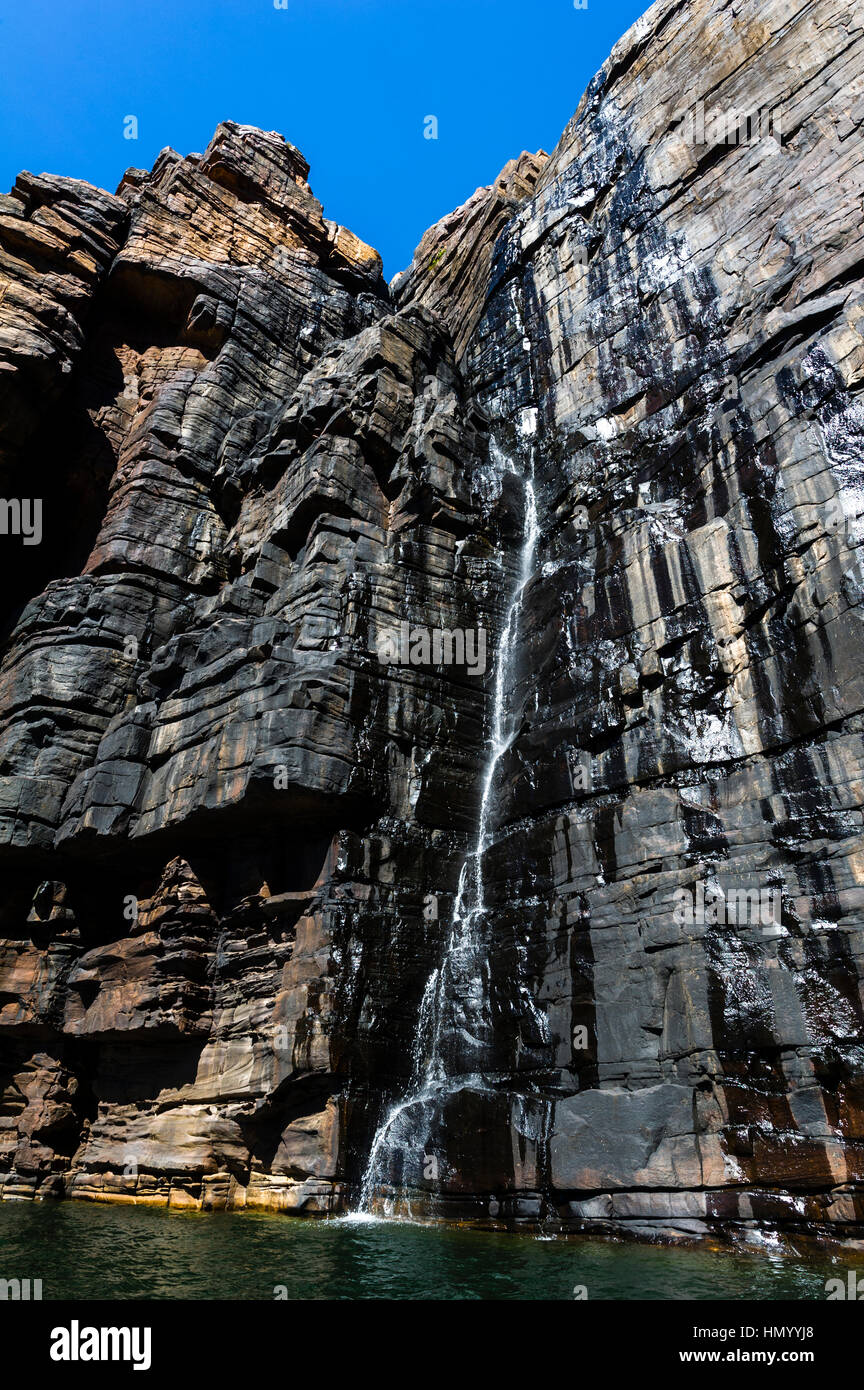 Ein Wasserfall Kaskaden hinunter eine schiere Sandstein in Cyanobakterien bedeckt. Stockfoto