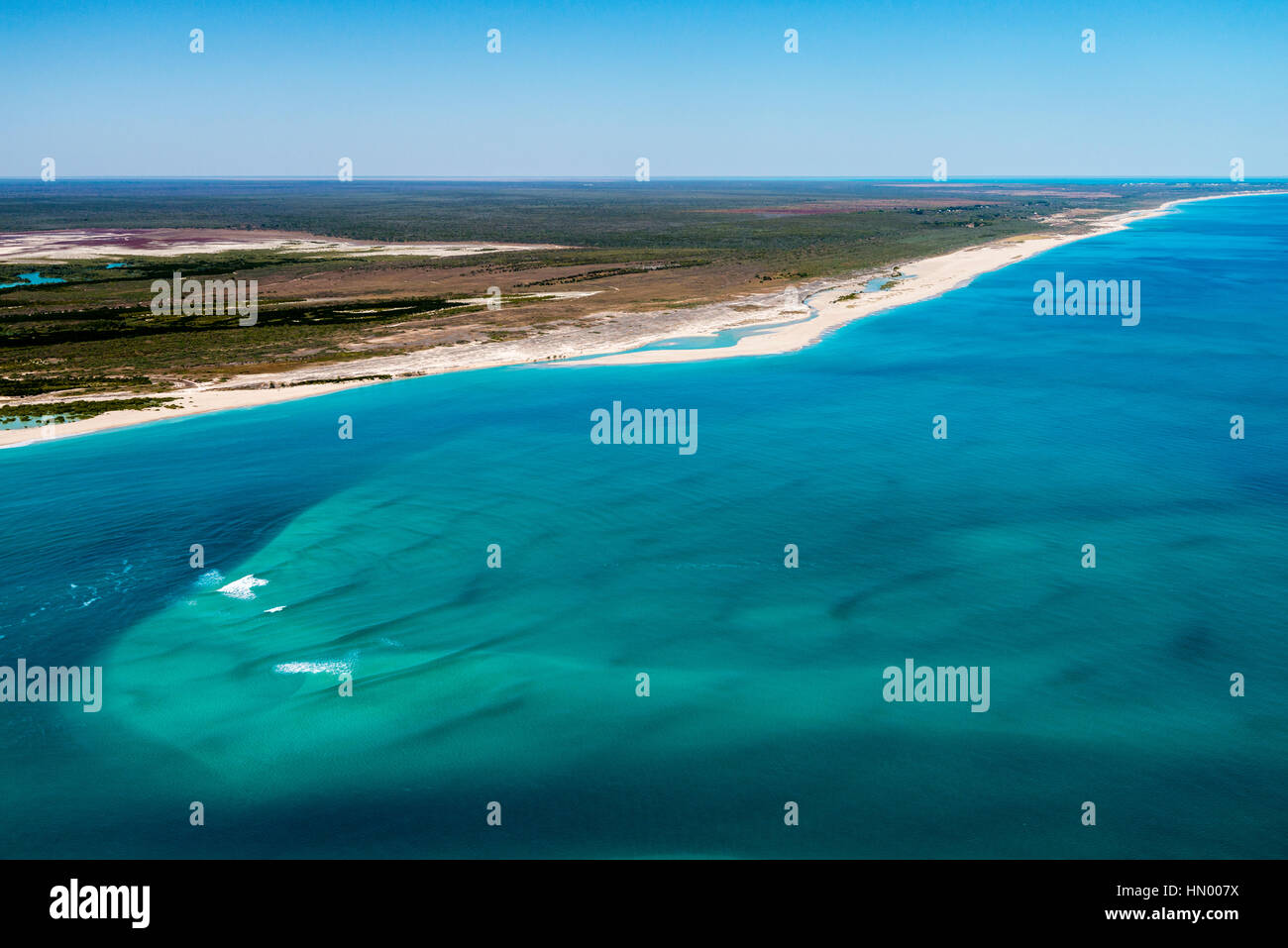 Eine unbewohnte endlosen weißen Sandstrand entlang einem türkisfarbenen Meer. Stockfoto