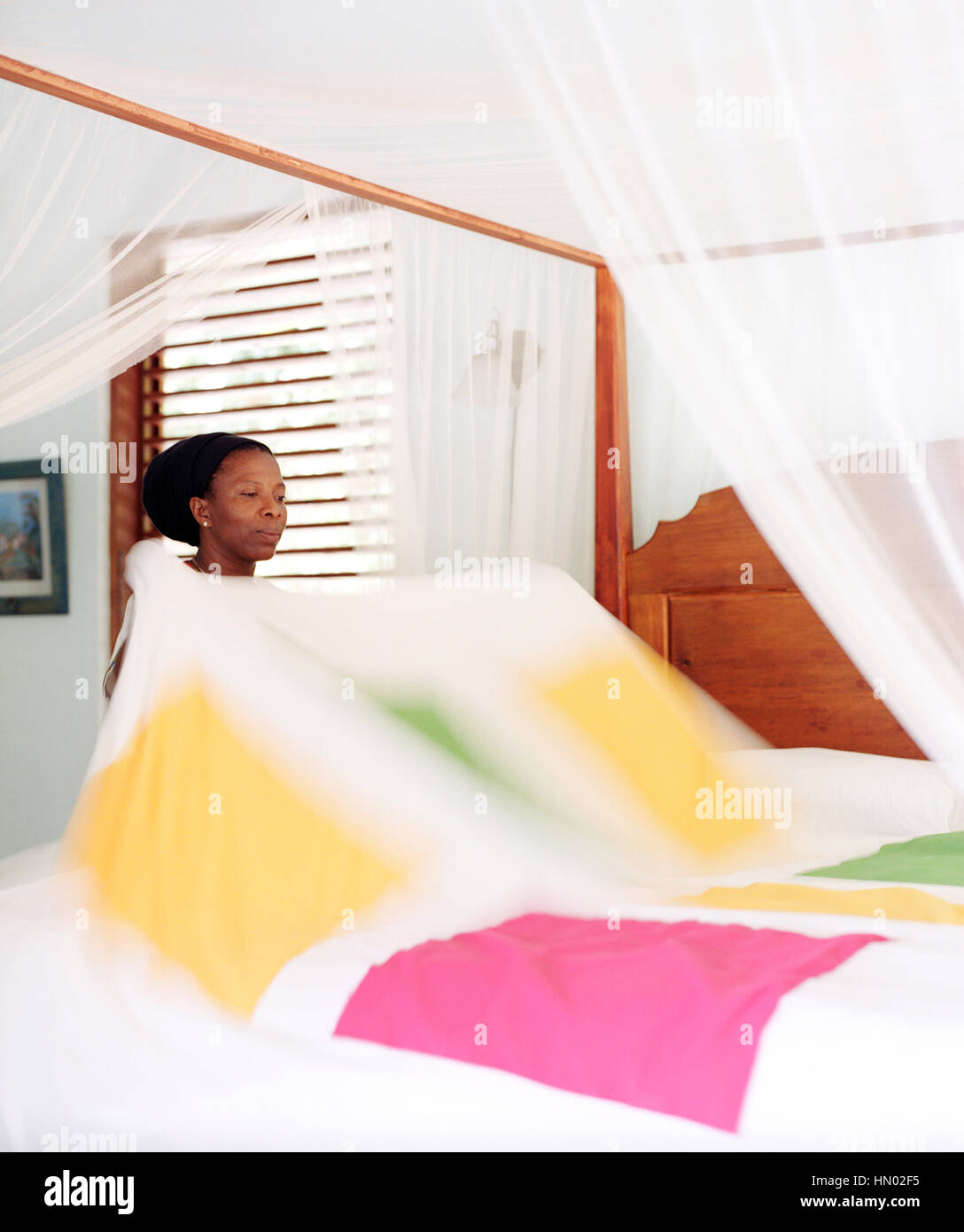 Eine Haushälterin macht ein Bett in der Hibiscus Villa im Steinfeld Estate Villa Resort in St. Lucia. Soufrière, St. Lucia Stockfoto