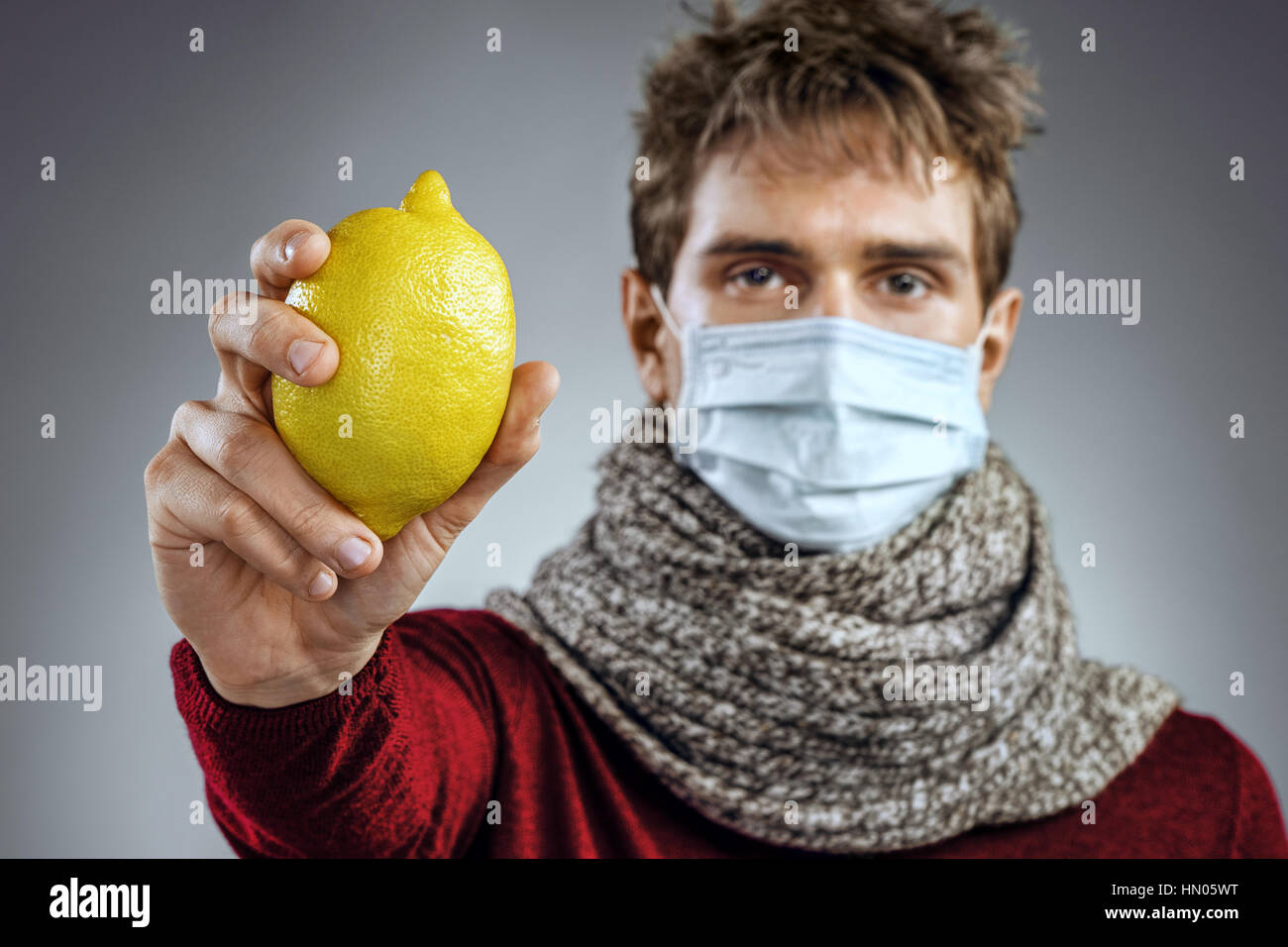 Kranker Mann Betrieb Zitrone. Foto des Mannes trägt Schutzmaske gegen Infektionskrankheiten und Grippe. Medizinisches Konzept Stockfoto