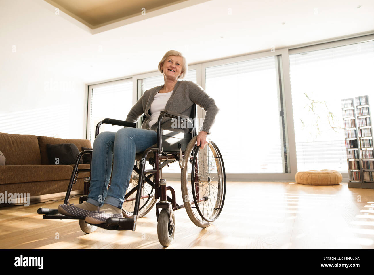 Behinderte ältere Frau im Rollstuhl zu Hause im Wohnzimmer. Stockfoto