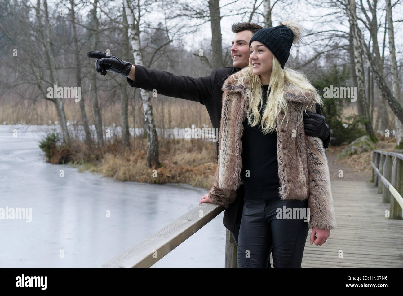 Schwedisches Ehepaar in Winterlandschaft. Blonde Frau mit schwarzen hat.hugged durch Braunhaarige Mann. Liebe und Freude Stockfoto