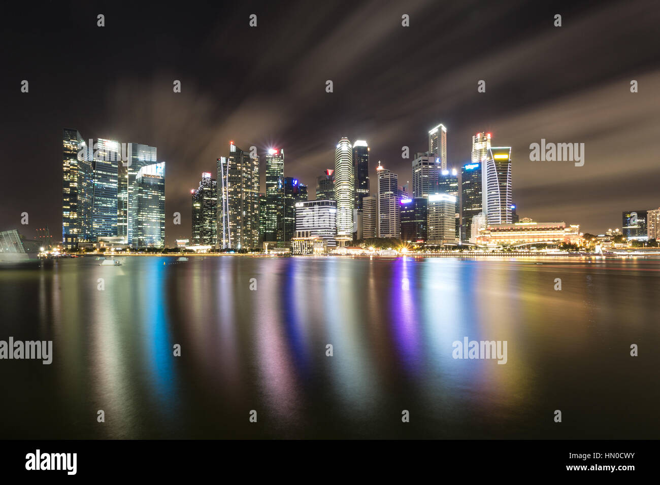 Eine Reflexion von den Wolkenkratzern der Geschäft Bezirk Skyline von Singapur in die Marina Bay von der Uferpromenade entfernt. Aufnahme mit langer Belichtungszeit zu smo Stockfoto