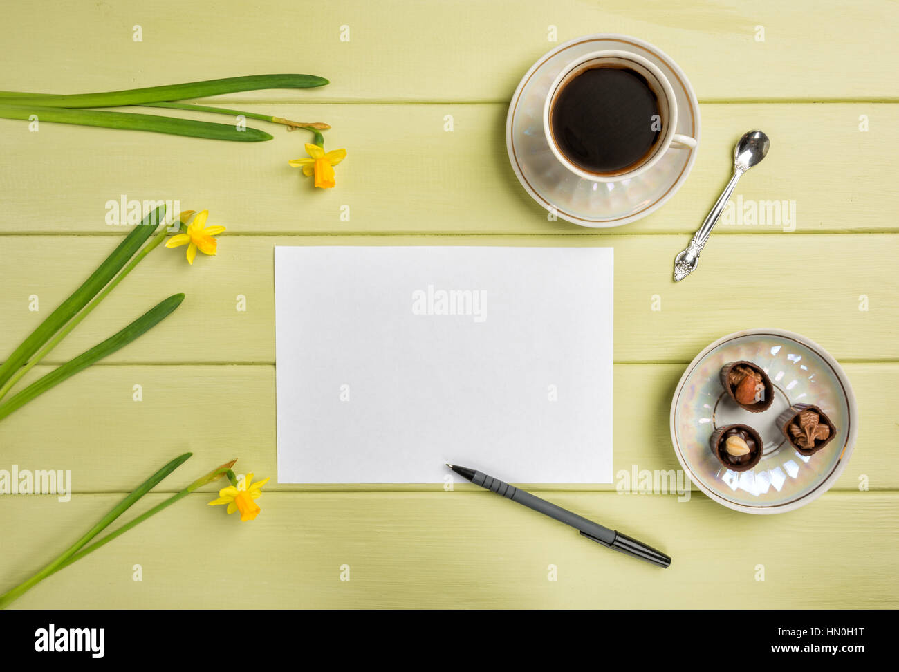 Papier, einen Stift, Tasse schwarzen Kaffee und Blumen auf einem hölzernen Hintergrund. Ansicht von oben. Kopieren Sie Raum. Stockfoto