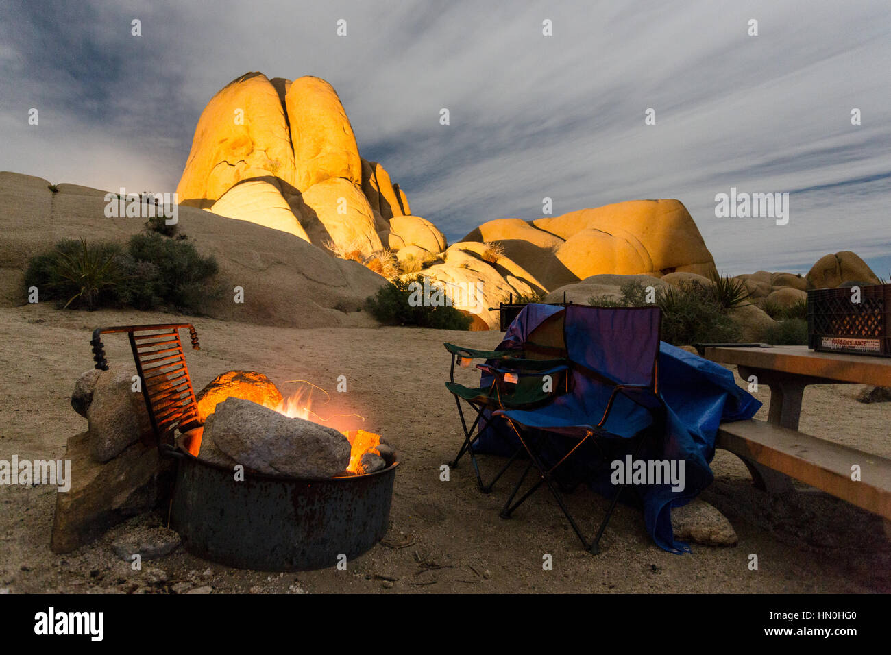 Ein Lagerfeuer brüllt im Mondschein an einem Standort in Jumbo Rocks Campground im Joshua Tree National Park. Stockfoto