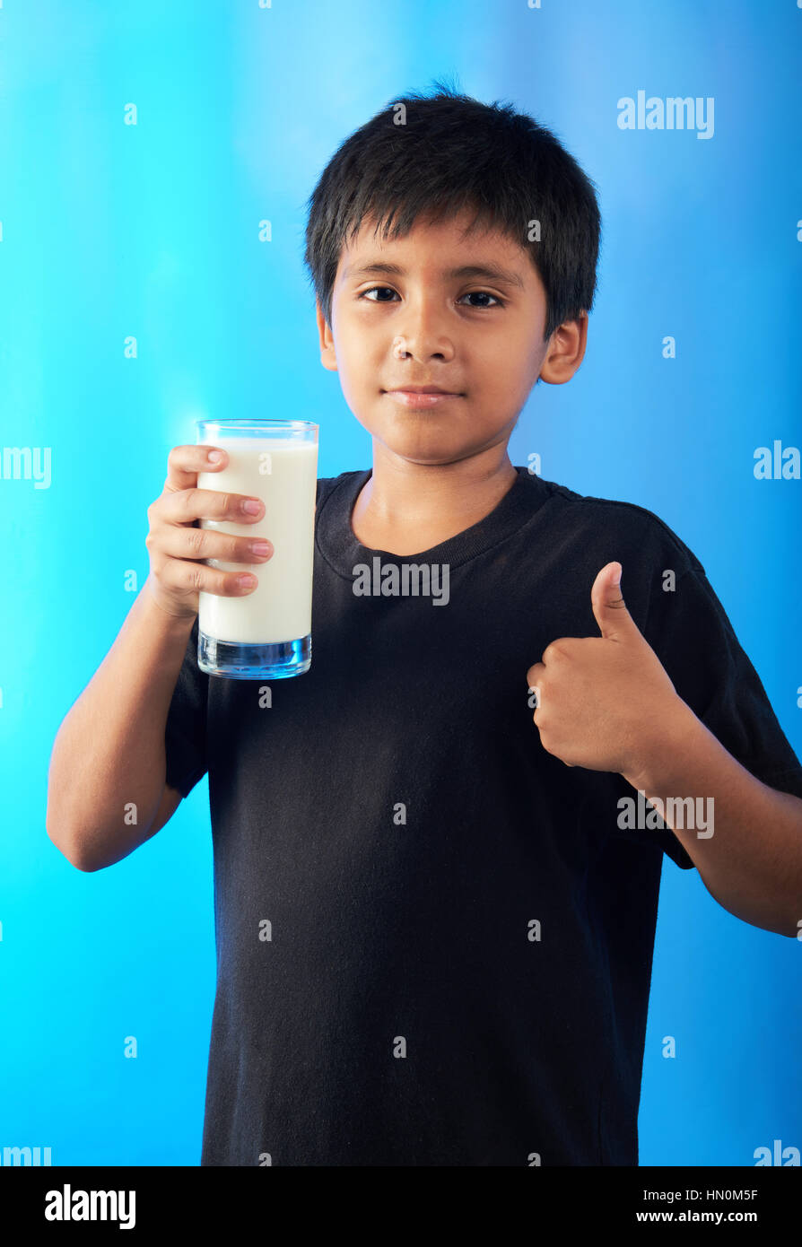 Junge mit Mlik auftauchend Daumen auf blauem Hintergrund Stockfoto