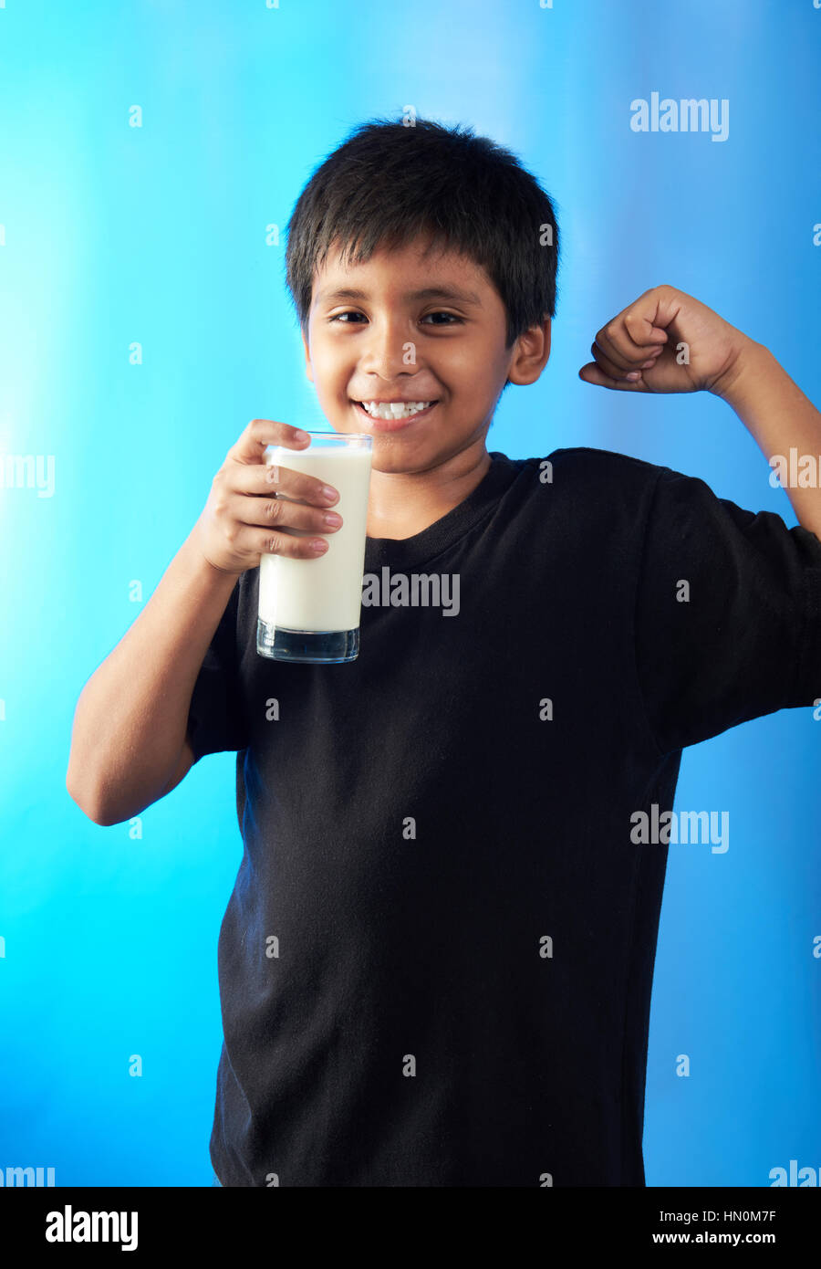 jungen zeigen Muskel hält Milch isoliert auf blauem Hintergrund Stockfoto