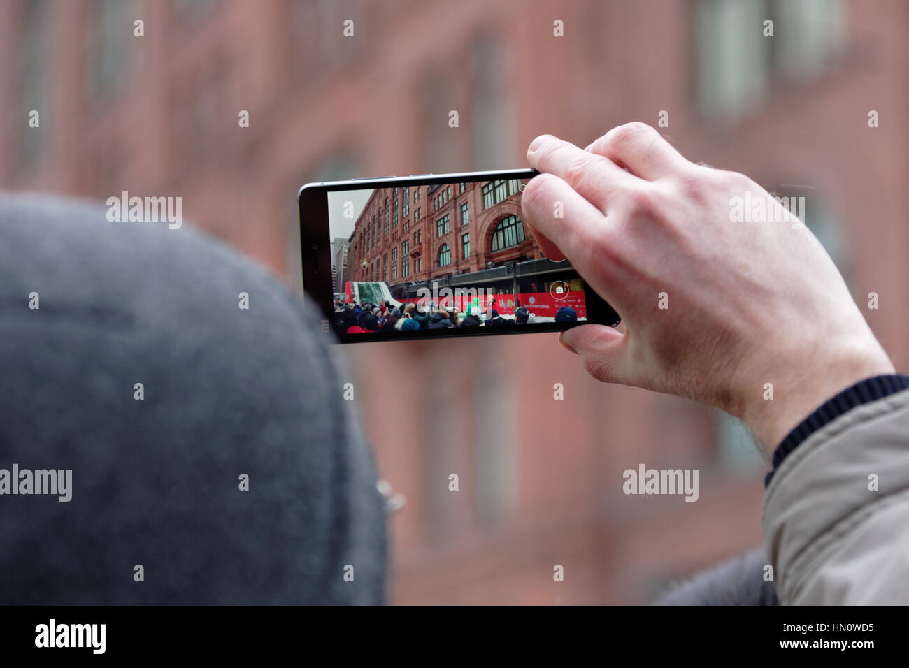 Ein Mann fotografiert mit seinem Cel Telefon während ein outdoor-Event im winter Stockfoto