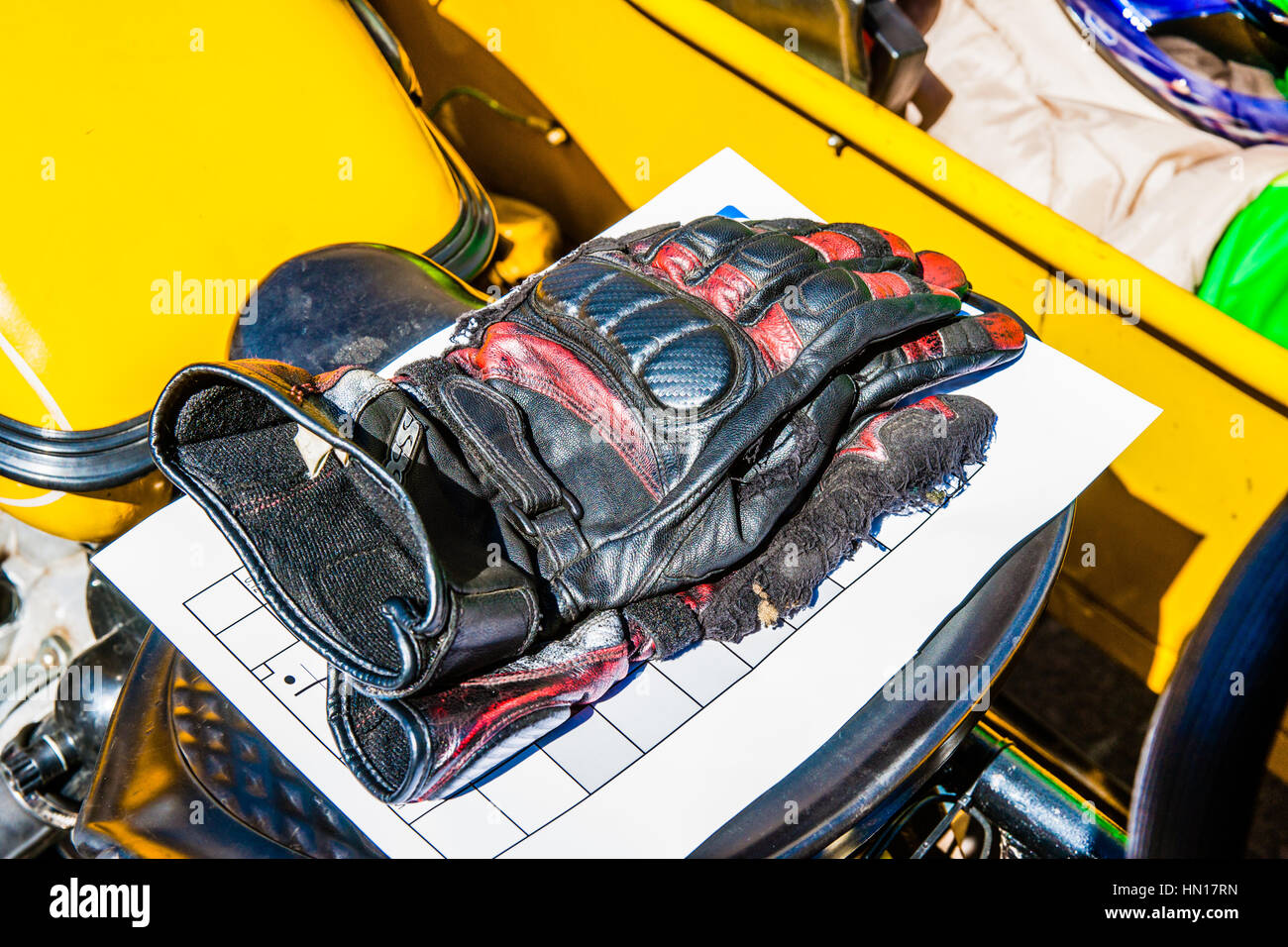 Farbe und Schönheit von Oldtimern. Schwarze Handschuhe eines Bikers auf einem Vordersitz ein Oldtimer Motorrad von gelber Farbe. Stockfoto