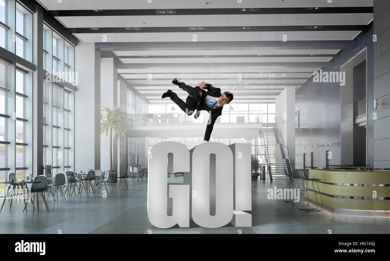 Fröhliche Jungunternehmer tanzen in seinem Büro. Mixed-media Stockfoto