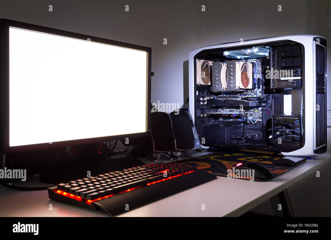 Auf Mass gefertigt-Gaming-Computer mit weißer Bildschirm, Tastatur, Maus, Desktop, Komponenten, Hardware, Gaming-Stuhl unter schlechten Lichtverhältnissen. Se Stockfoto