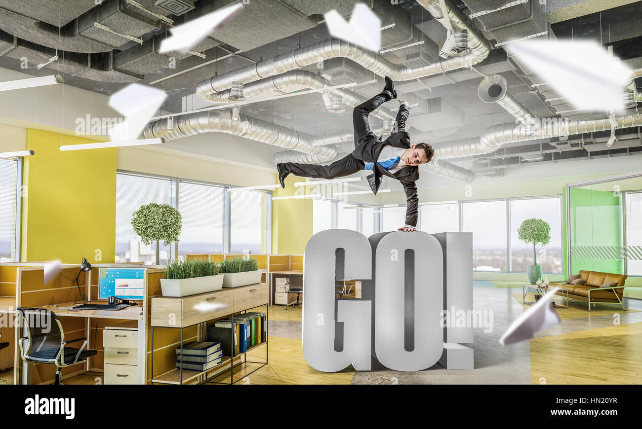 Fröhliche Jungunternehmer tanzen in seinem Büro. Mixed-media Stockfoto