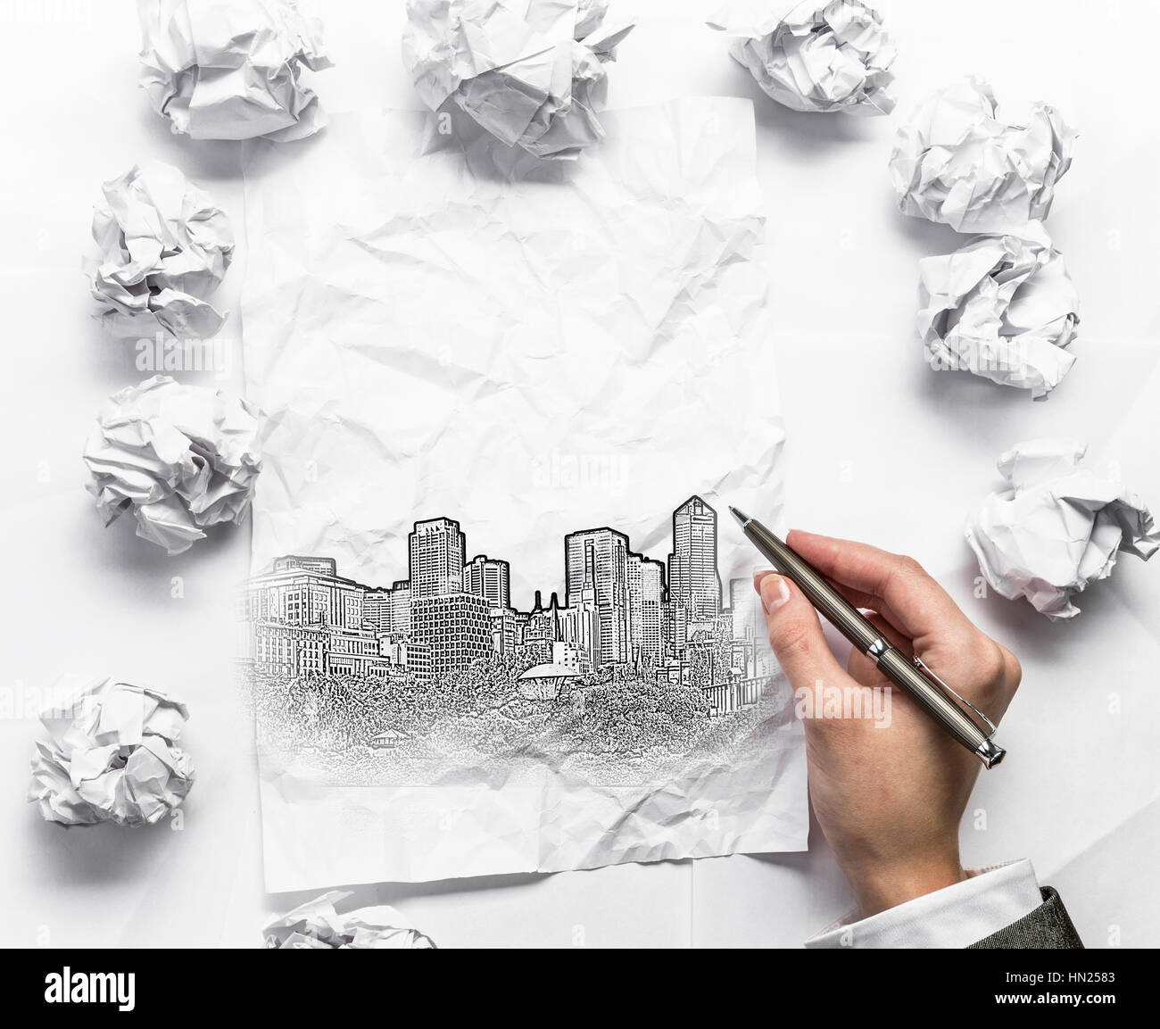 Hand der Geschäftsfrau Gebäude auf zerknittertes Papier zeichnen Stockfoto