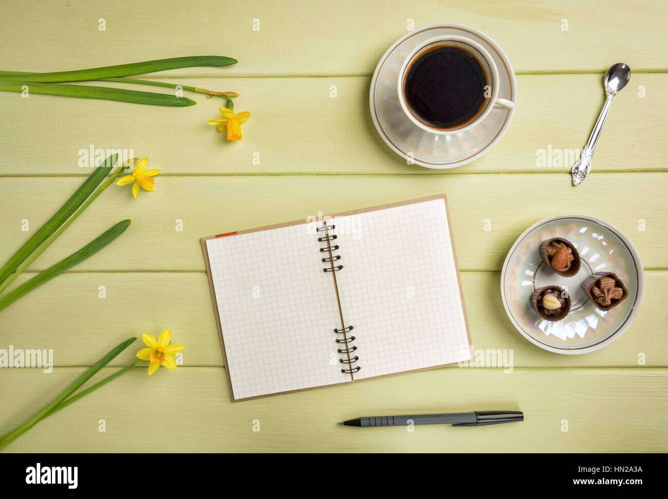 Notebook, einem Stift, Tasse Kaffee und Blumen auf einem hölzernen Hintergrund. Ansicht von oben. Kopieren Sie Raum. Stockfoto