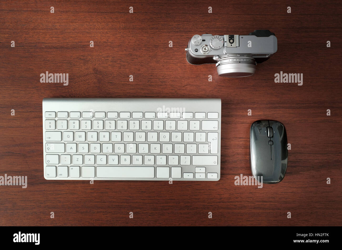 Spiegellose Digitalkamera, Maus und Tastatur auf braunen Holz Schreibtisch Stockfoto