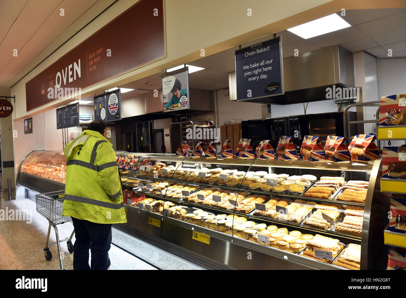 Ein Arbeiter kauft Torten in einem Supermarkt aus dem frisch Ofen-Abschnitt. Stockfoto