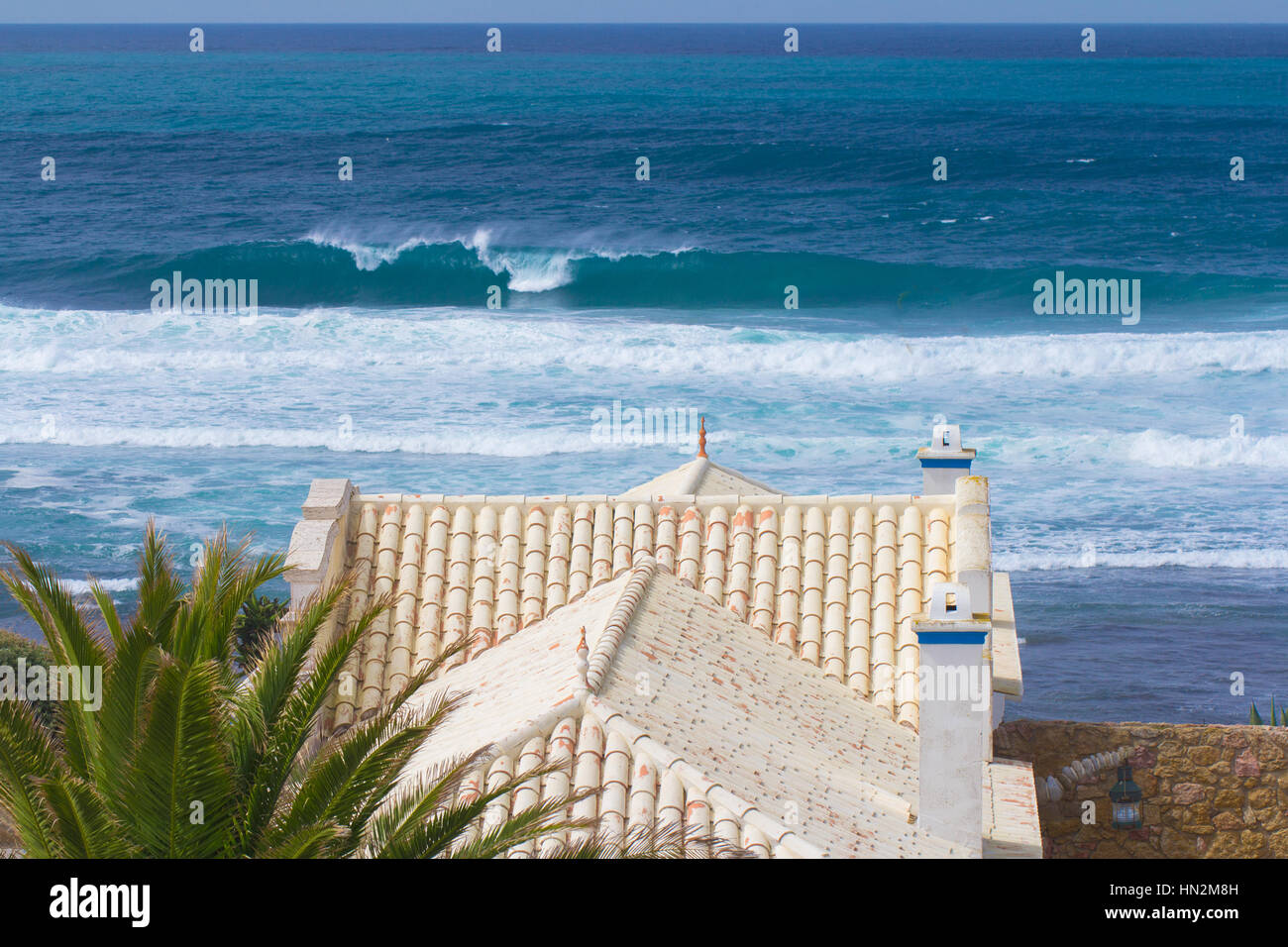 Blick auf das Ziegeldach eines Luxus am Wasser tropische Villa und Palm Baumes mit Blick auf das Meer und Strand konzeptionelle von einem Sommerurlaub und Ferien Stockfoto