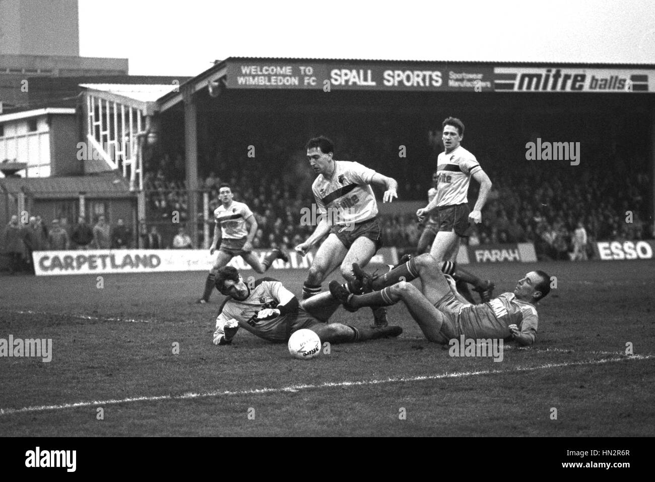 Wimbledon Alan Cork (rechts) landet auf dem Boden nach seinem Schuss auf das Tor von Watford Torwart Tony Coton, während heutige Barclays League Division One gespeichert bei Plough Lane, Wimbledon-Spiel. Mitspieler Watford in der Box sind John McClelland (stehend rechts) und Mark Morris (Mitte). Stockfoto