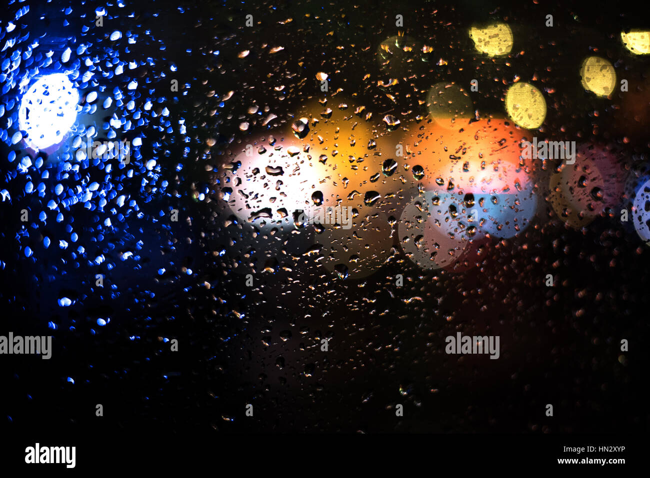 Tropfen Wasser auf Glas-Fenster mit Bokeh Ampeln in dunklem Hintergrund Stockfoto