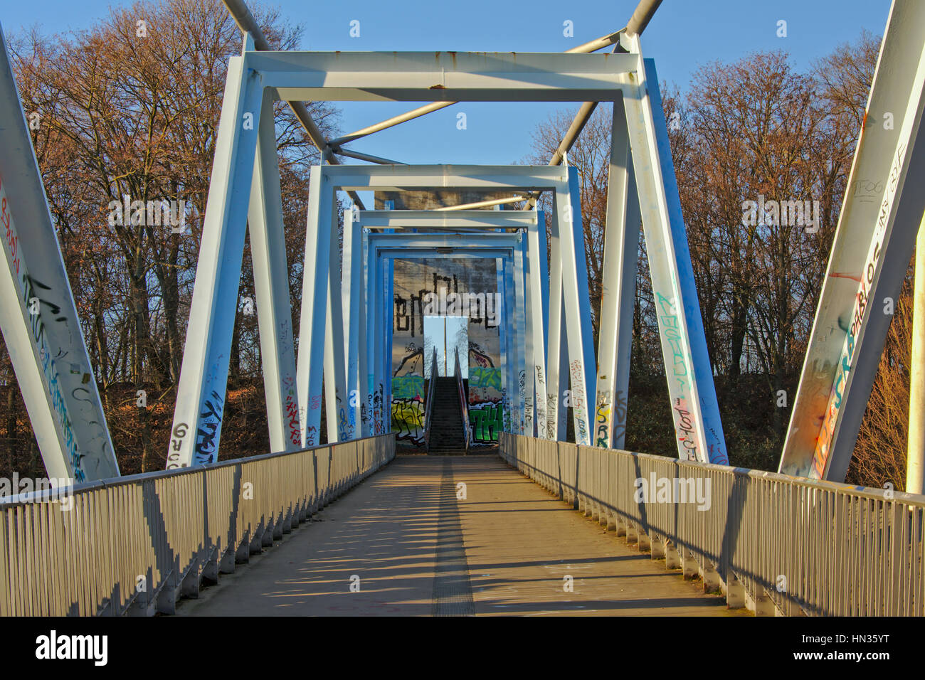 Pedestrain Russ Brücke mit leichten blauen Metallbau und Graffiti, führt zu einer Treppe und Bäume Stockfoto