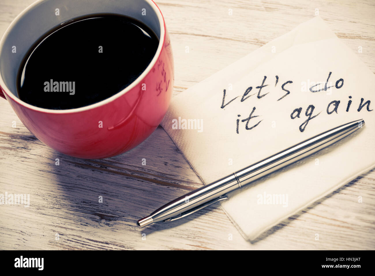 Tasse Kaffee und Serviette mit Schriften auf Tisch Stockfoto