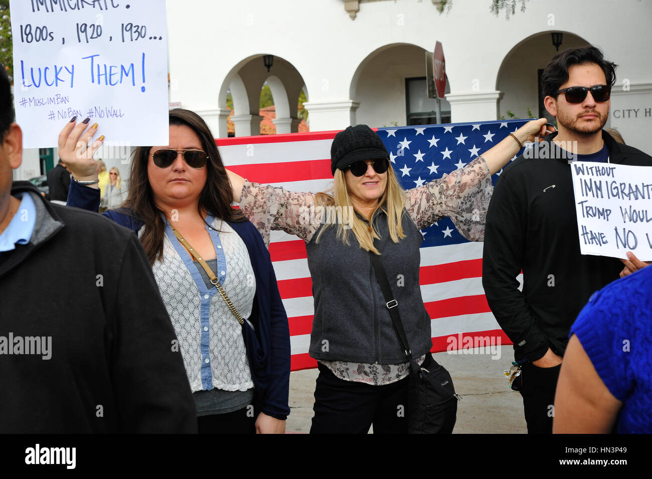 Demonstranten mit Zeichen und eingehüllt in die amerikanische Flagge bei einer muslimischen Reiseverbot Anti-Rallye in Santa Barbara, Kalifornien Stockfoto