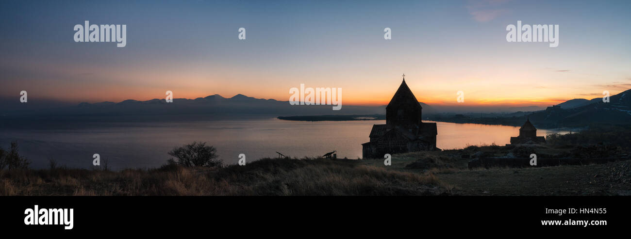 Panoramasicht auf die Tempelanlage auf dem Sevan See bei Sonnenuntergang, Armenien. Silhouetten der St. Jakob Kirche und Sevanavank. Armenische Sehenswürdigkeiten Stockfoto