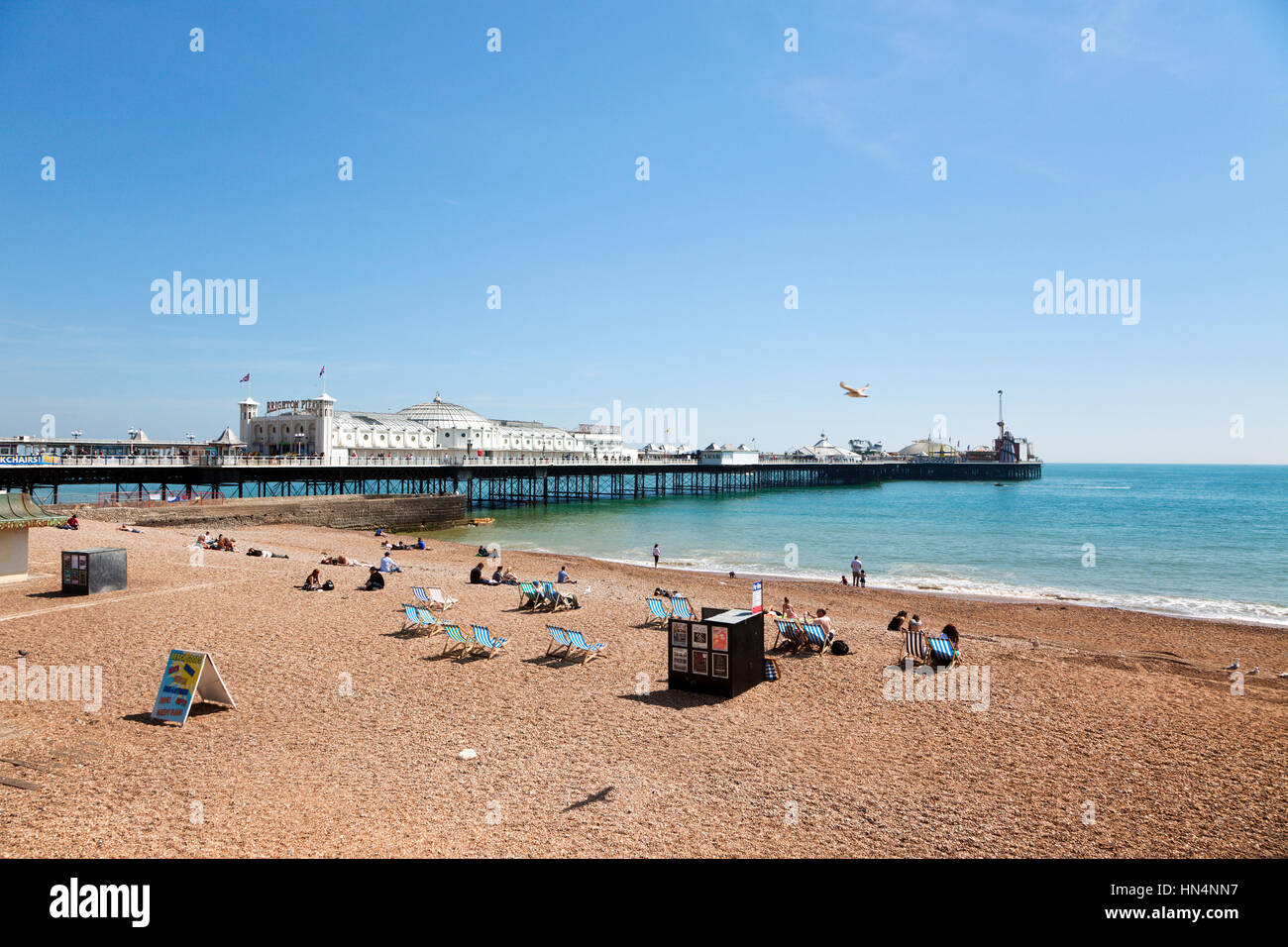 Brighton, Sussex, Vereinigtes Königreich - 16. Mai 2014: Touristen Entspannung am Strand neben dem Brighton Pier aus dem Jahre 1899. Brighton ist das größte und Stockfoto