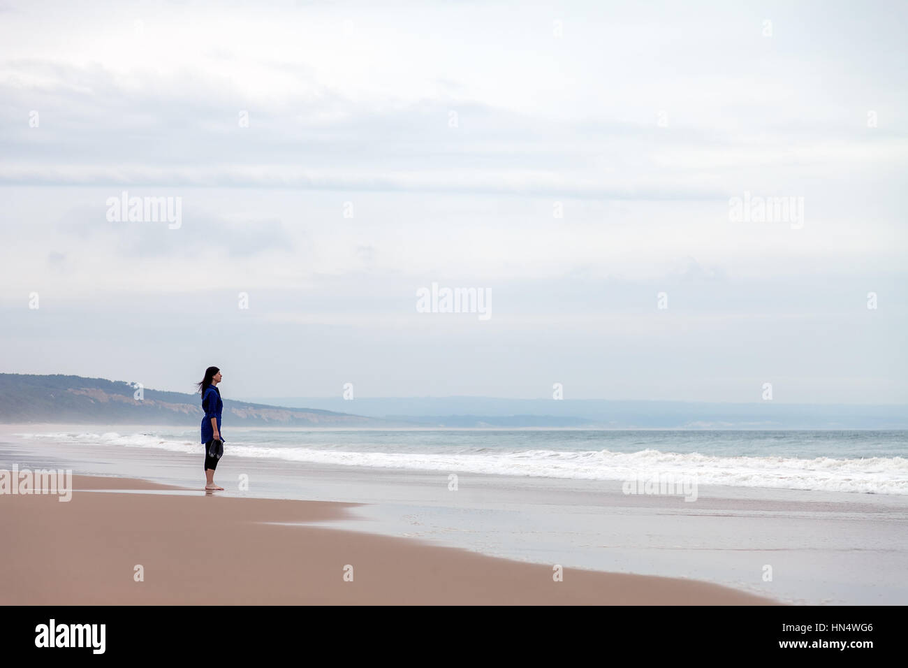Einsam und depressiv Frau das Meer in einem verlassenen Strand auf einen Herbst Tag-/frau Strand allein einsam traurig traurig, deprimiert beobachten, Meer Stockfoto