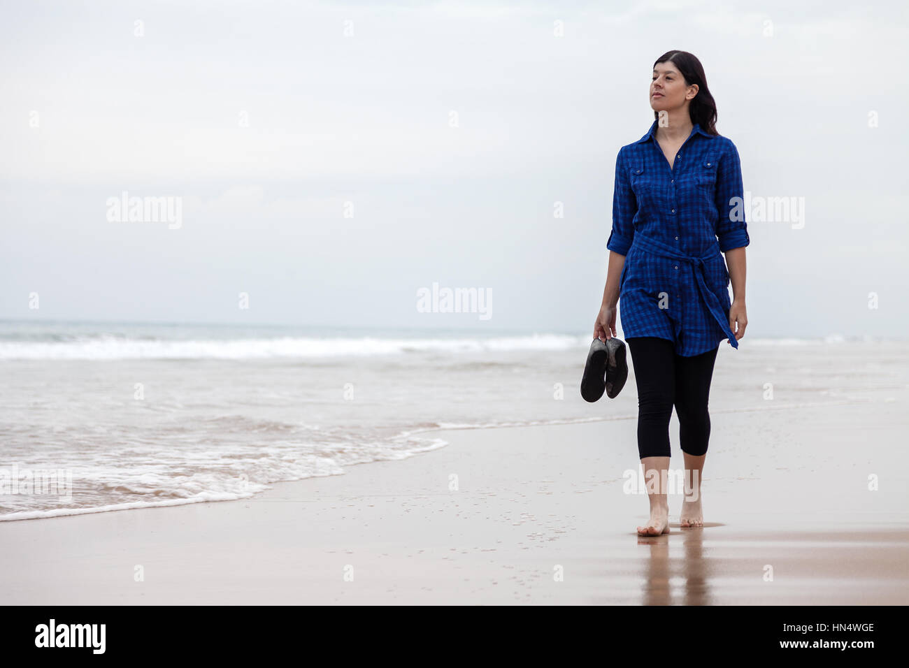 Junge Frau alleine in einer verlassenen Strand auf einen Herbst Tag-/frau Strand allein einsame traurige Traurigkeit Depression depressiv locker fallen Stockfoto