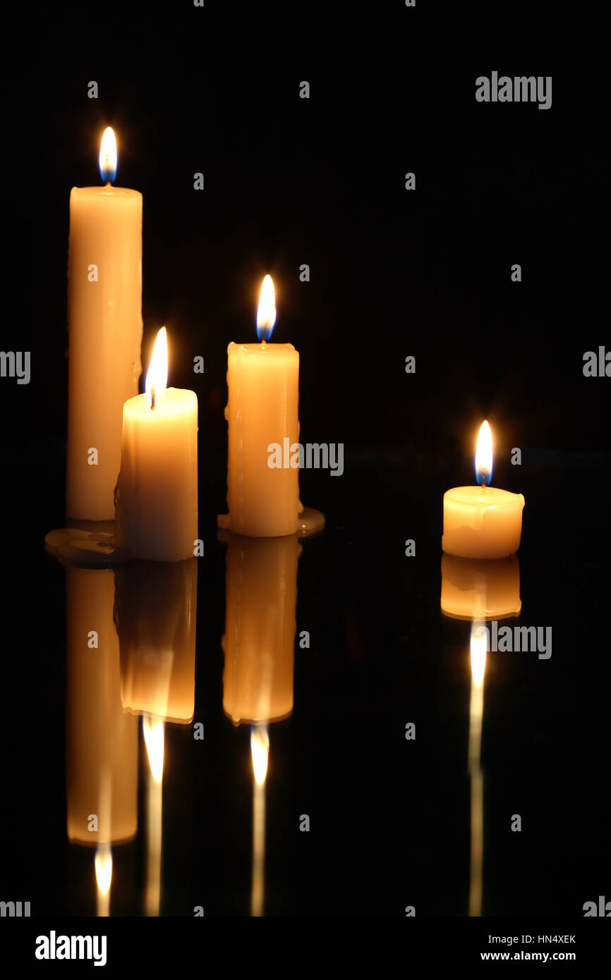 Satz von Anzünden von Kerzen in einer Reihe auf dunklem Hintergrund mit Nachhall Stockfoto