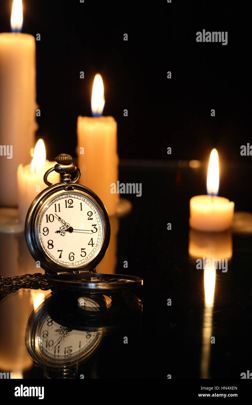 Taschenuhr in der Nähe von Anzünden von Kerzen auf dunklem Hintergrund Stockfoto
