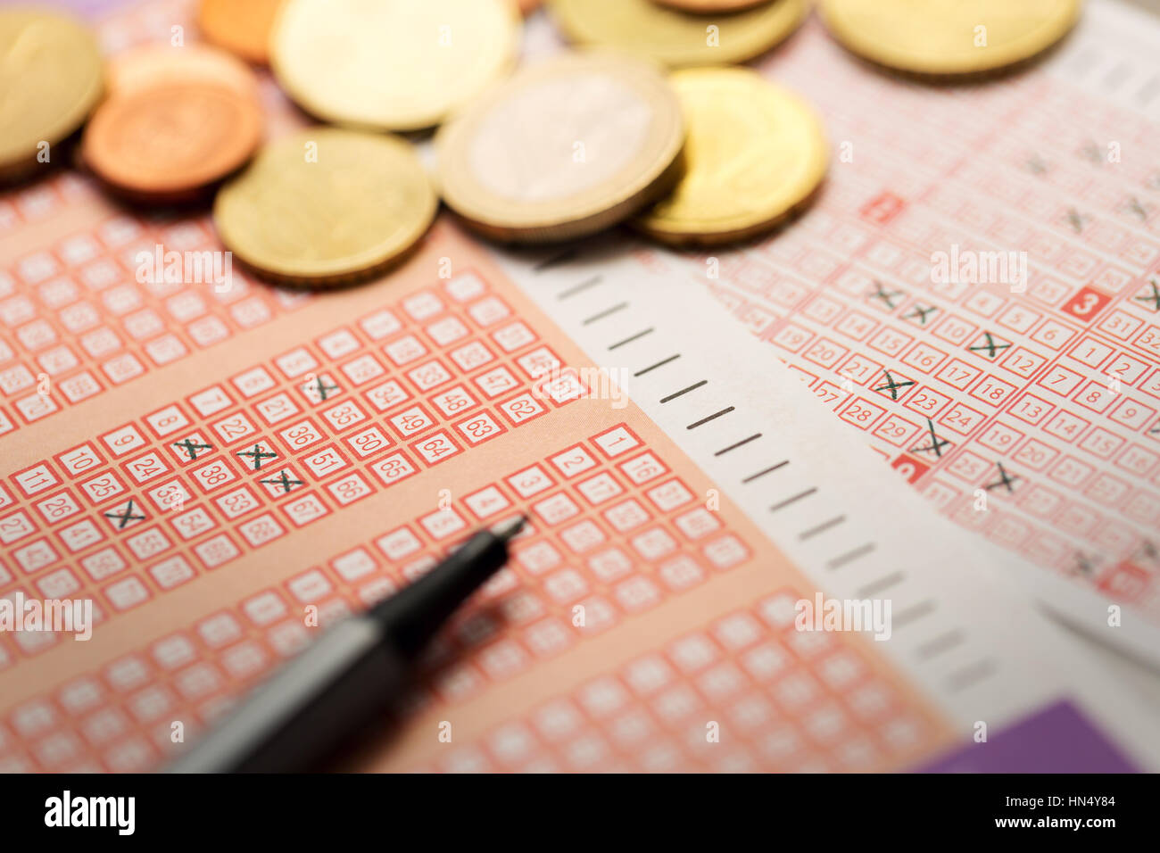 Lottoscheine mit Münzen und Stift Stockfoto