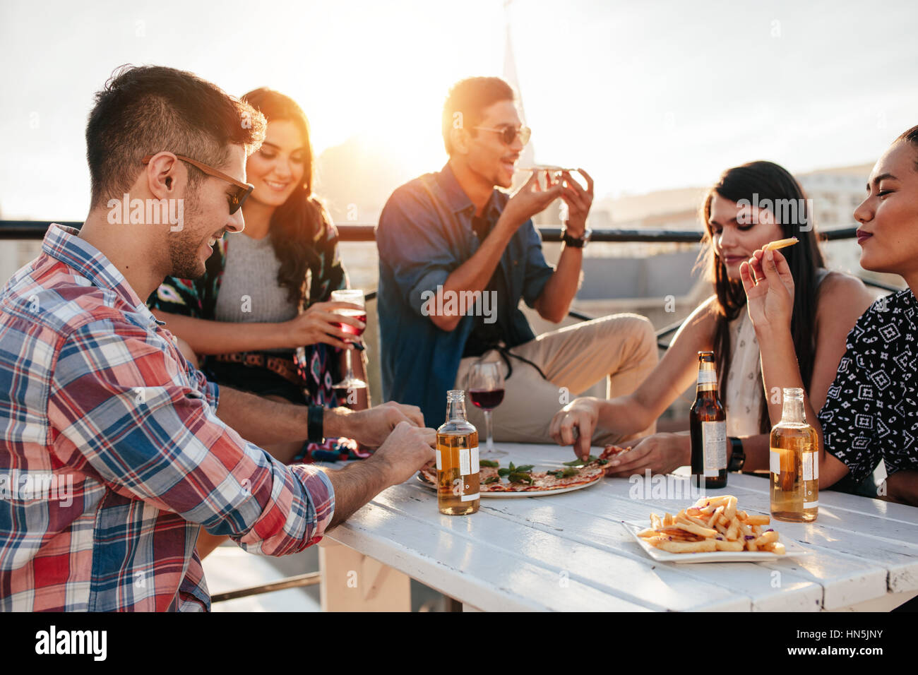 Gruppe junger Leute herumsitzen und Pizza essen. Freunde, Party und Pizza essen. Stockfoto