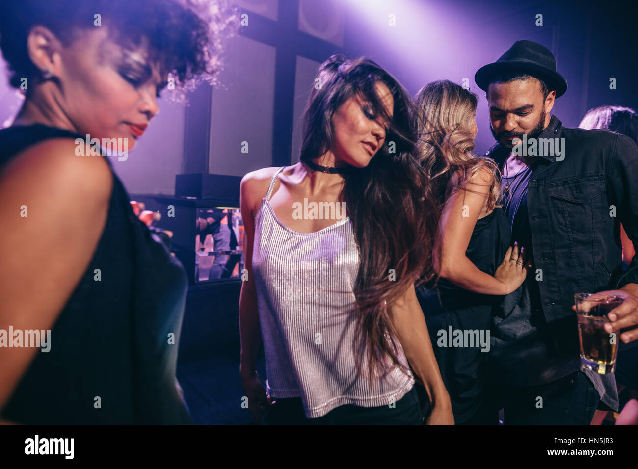 Junge Frau auf Party mit Freunden in der Nähe von tanzen. Gruppe von Jugendlichen, die Spaß am Nachtclub. Stockfoto