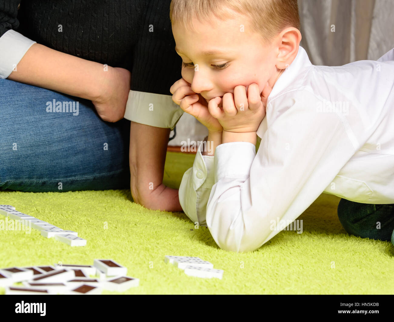 Kind mit seiner Mutter auf dem Teppich liegend Domino spielen Stockfoto