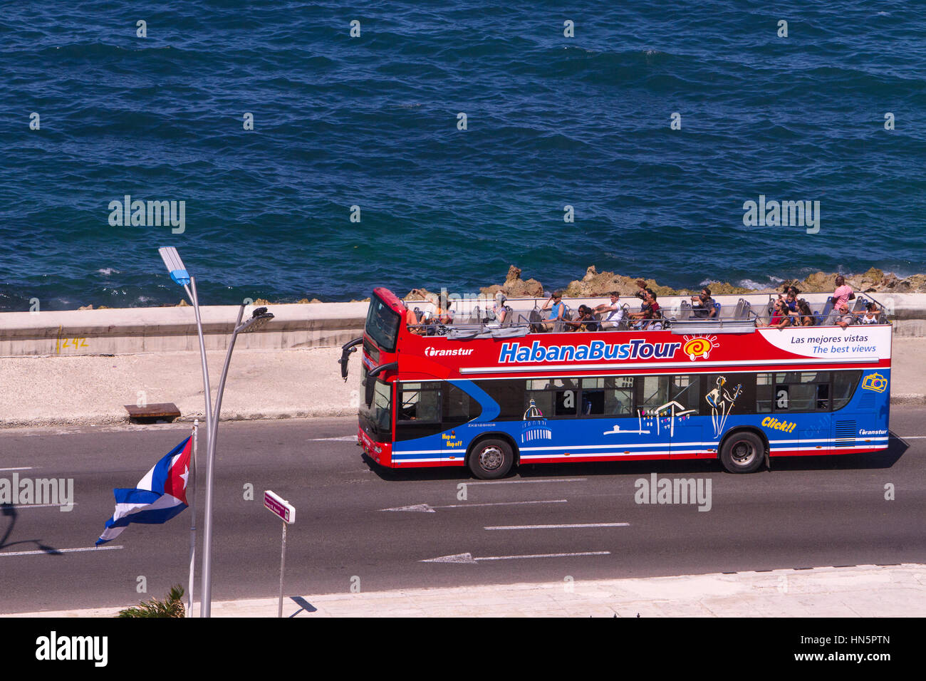 Touristen auf Havannas berühmten Küstenstraße El Malecon, einige Autos bringen Touristen andere sind den täglichen Transport für Kubaner, vom Hotel aus gesehen Stockfoto