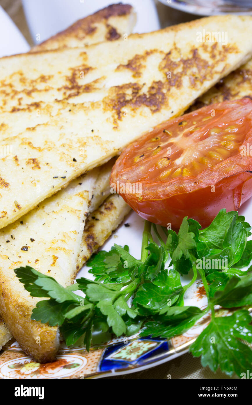 Nahaufnahme eines Teils der Zigeuner Toast serviert mit gegrillten Tomaten und Unterredung garnieren. Stockfoto