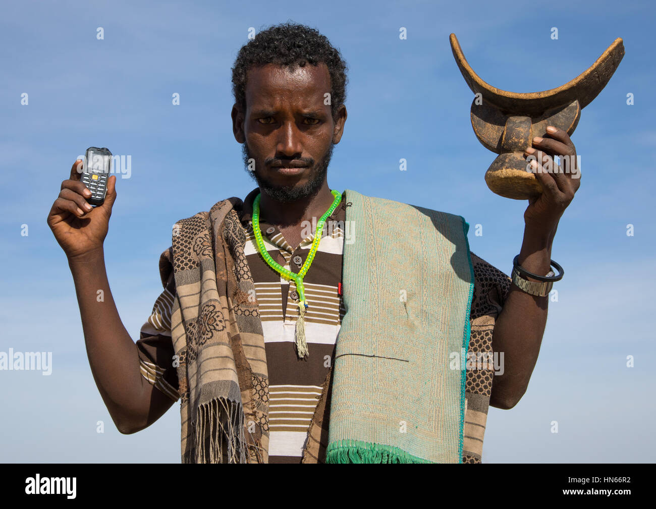Issa Stamm Mann hält ein Mobiltelefon und einem hölzernen Kissen, Afar Region, Yangudi Rassa Nationalpark, Äthiopien Stockfoto