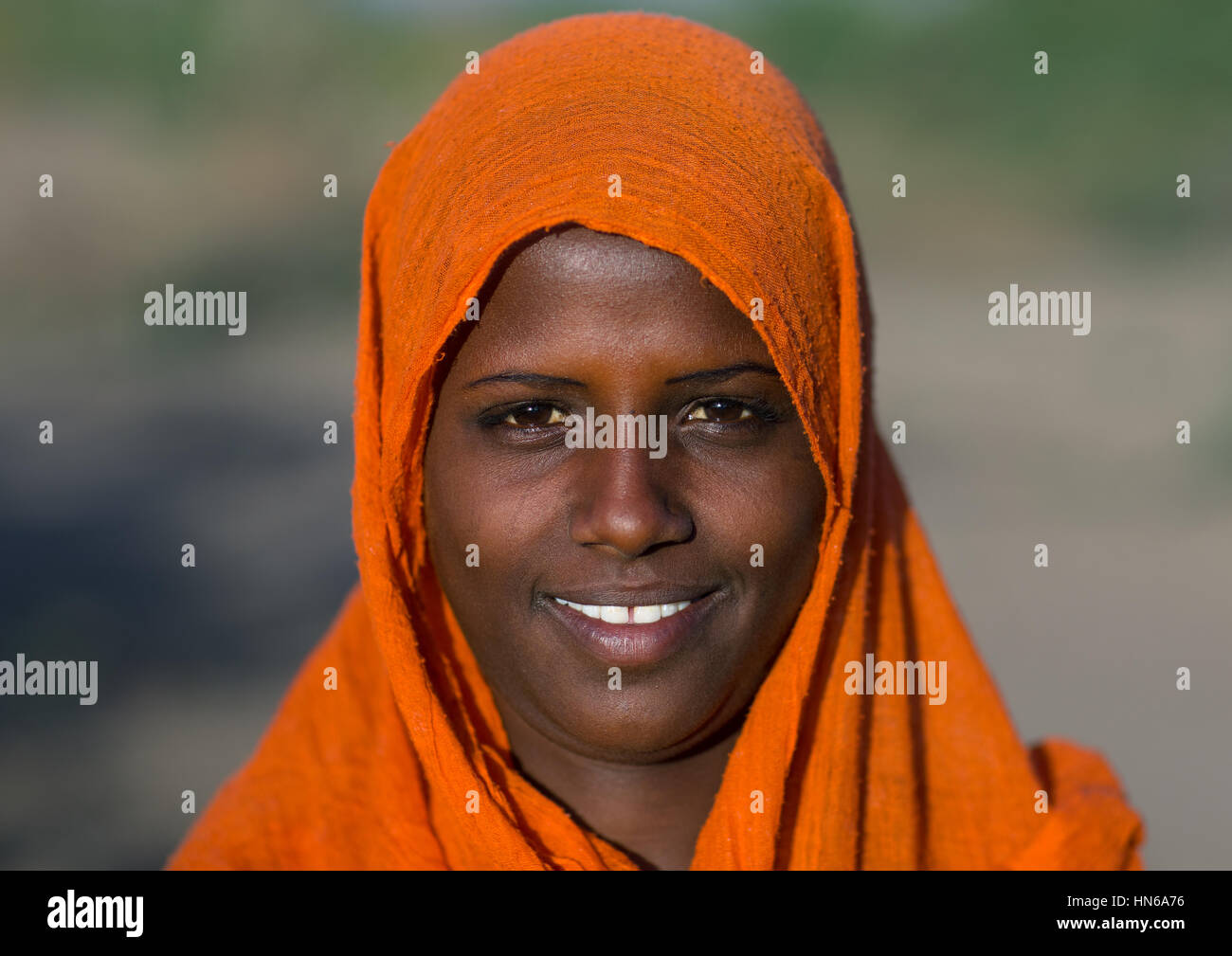 Porträt einer lächelnden Ferne Stamm Frau mit einem orangefarbenen Schleier, Afar-Region, Afambo, Äthiopien Stockfoto