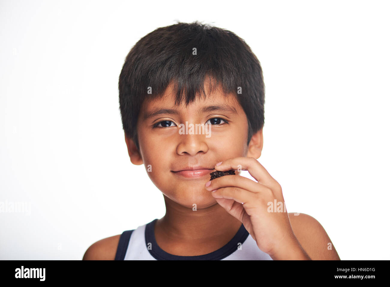 kleiner Junge Latino halten Schokoladenkuchen isoliert auf weiss Stockfoto