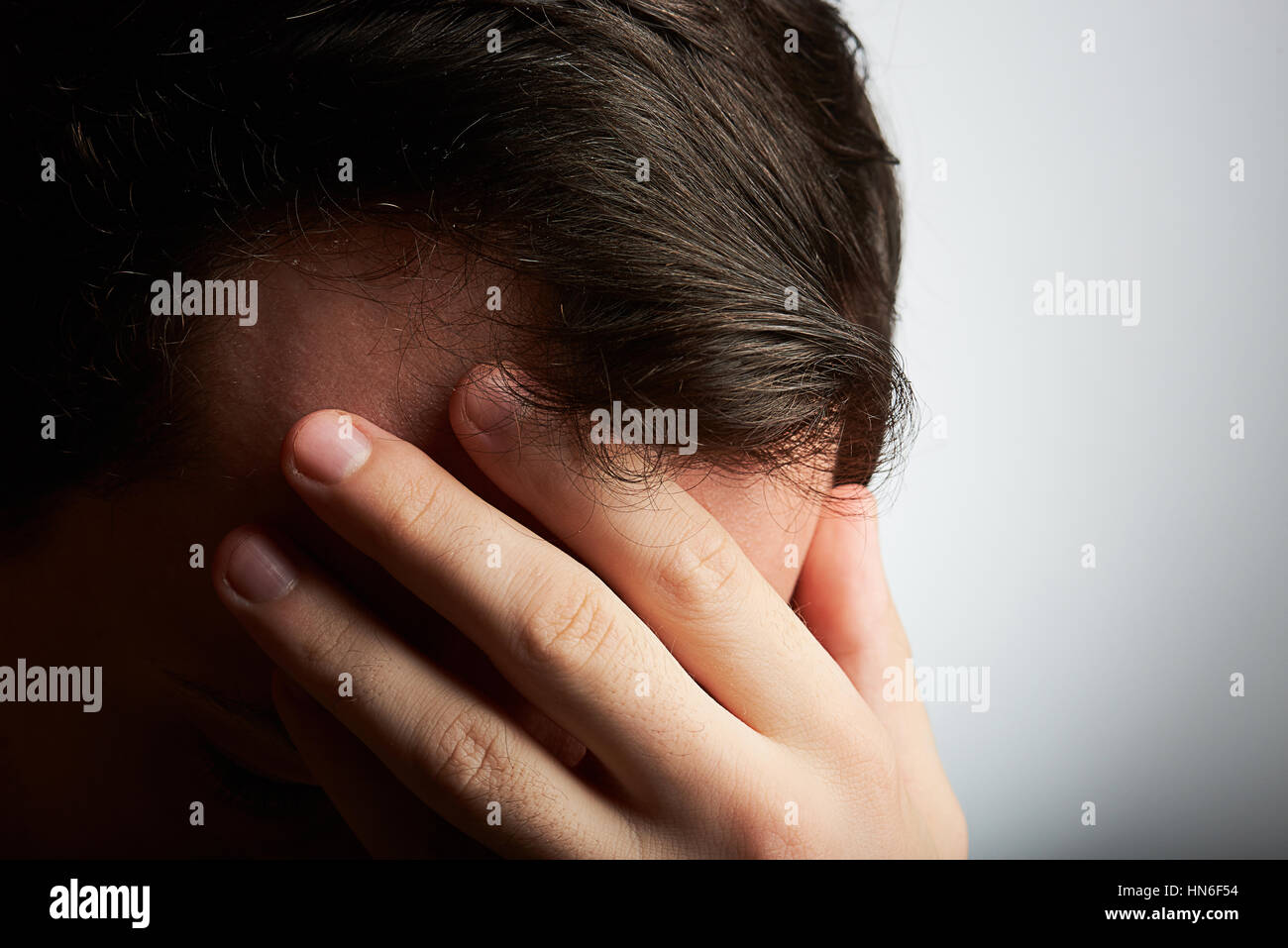 Manndeckung den Kopf mit der Hand unter Kopfschmerzen leiden Stockfoto