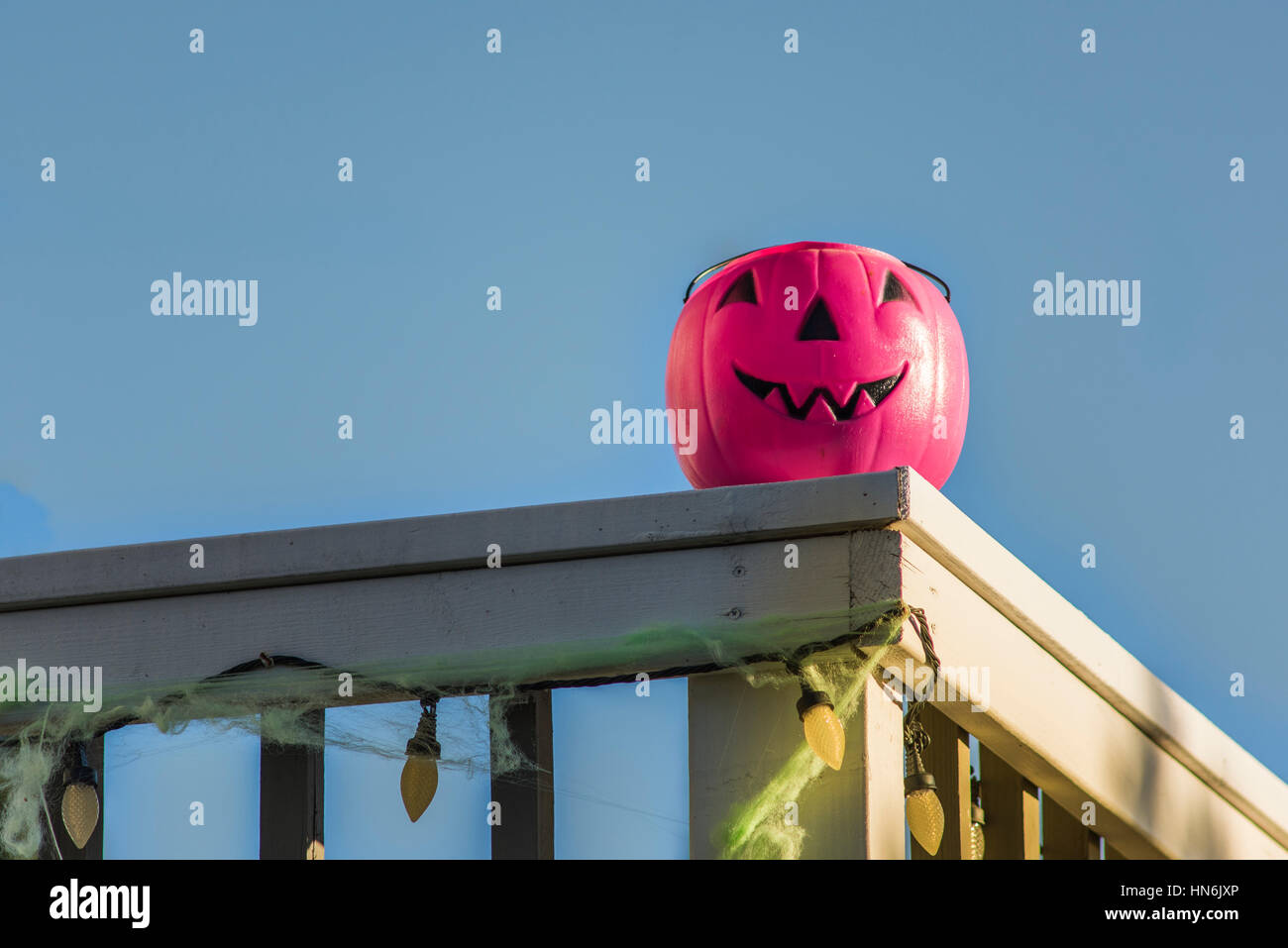 Halloween Kürbis Eimer auf Deck Geländer mit blauem Himmel und Beleuchtung Dekoration geschnitzt Stockfoto