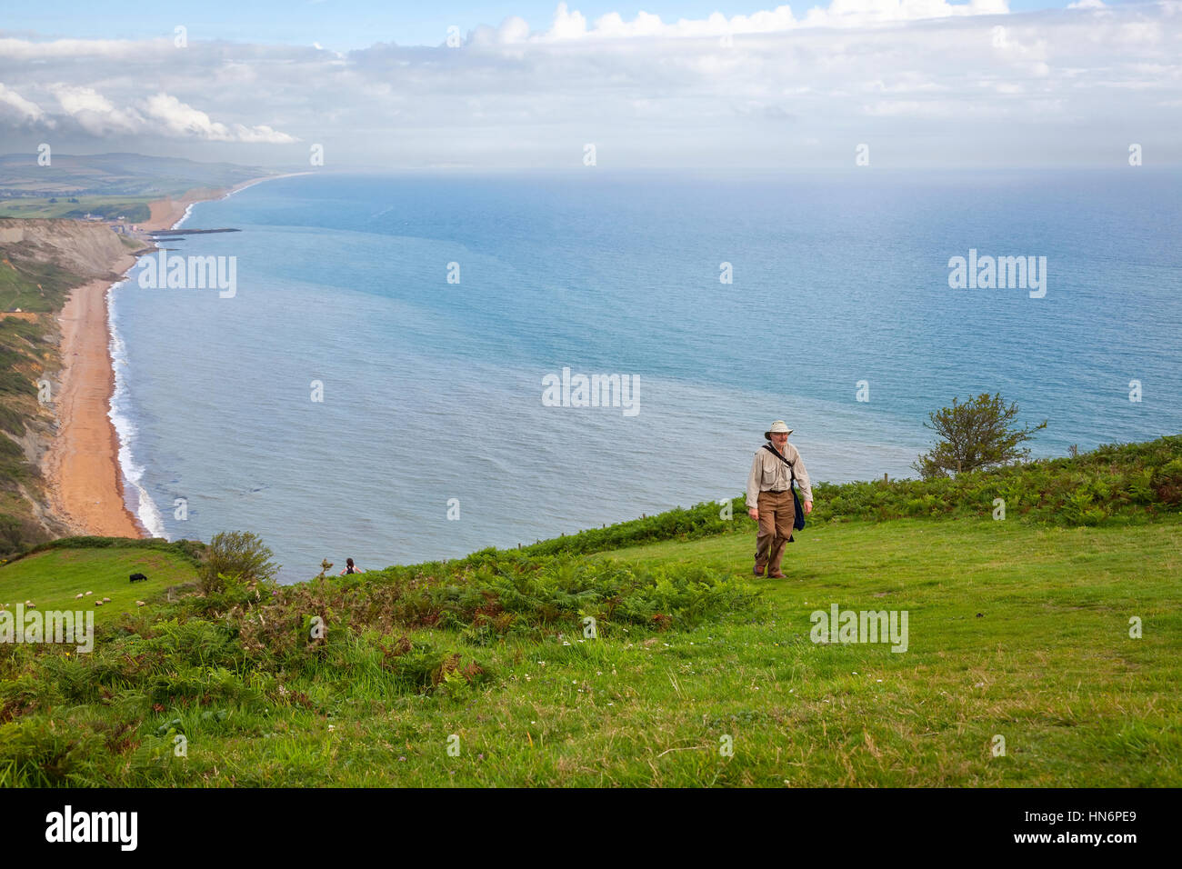 Ein Mann Klettern eines langen Hügels mit dem Atlantischen Ozean im Hintergrund entlang der South West Coast Path in Dorset, England. Stockfoto